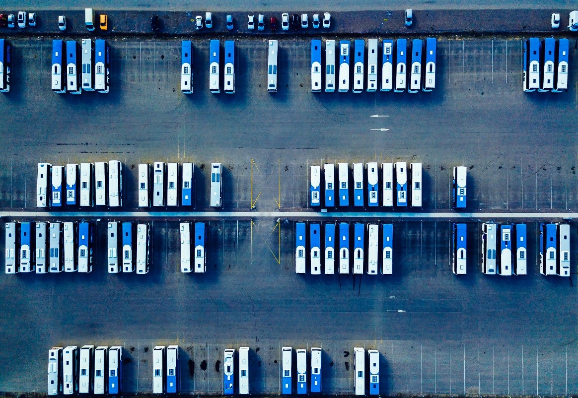 Aerial view of dozens of white and blue buses parking in a bus yard